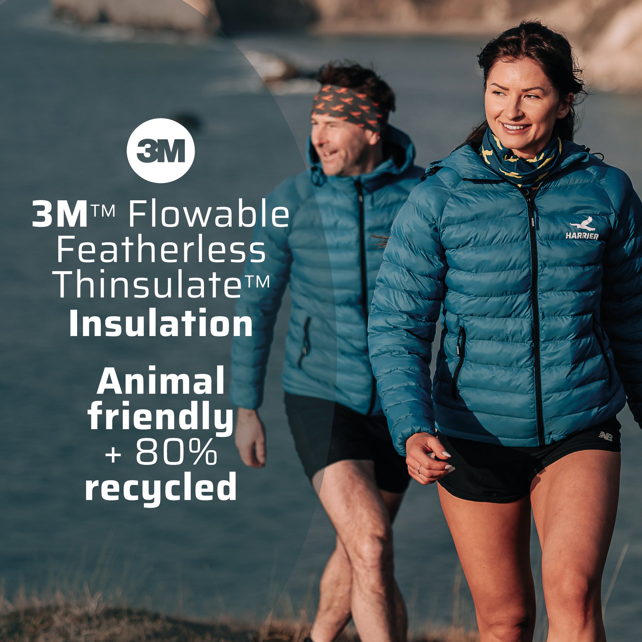 Woman and a man wearing the thermal jacket, walking along a coastline. They are smiling.