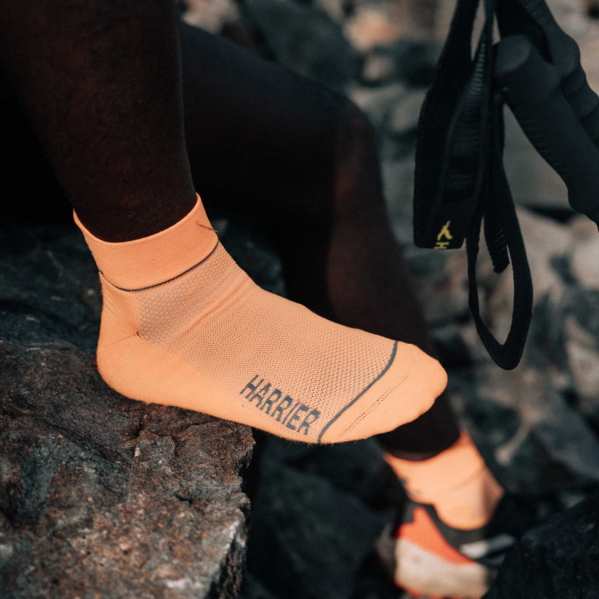 Close up of a persons foot resting on a rock. They are wearing bright orange socks.