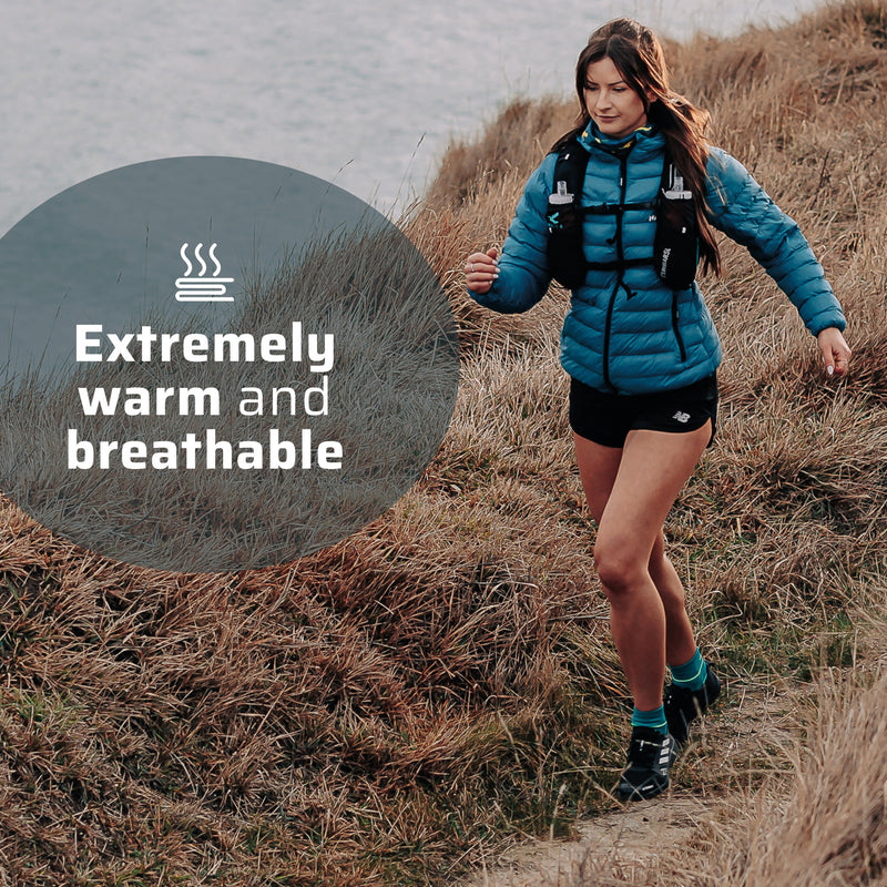 A woman wearing the thermal jacket running along a coast line. 