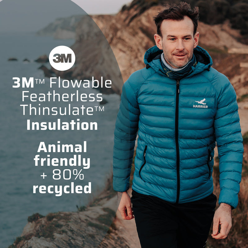 A man walking along a coastline wearing the thermal jacket. 