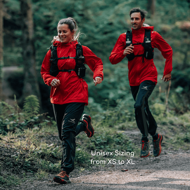A woman and a man running in the forest. They are both wearing a waterproof jacket and trousers.