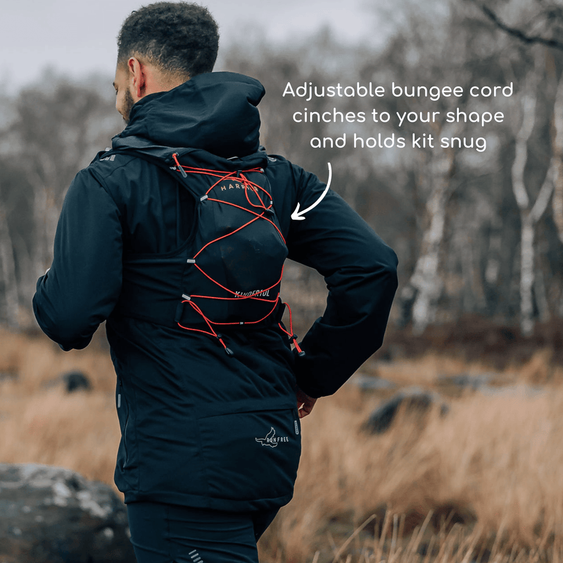 A man wearing a hydration vest, running in the countryside.  