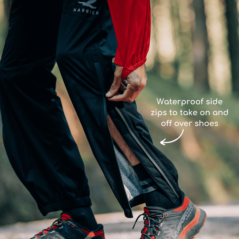 Close up of a persons legs wearing waterproof trousers. They are using the zip that runs from the knee to the ankle. 