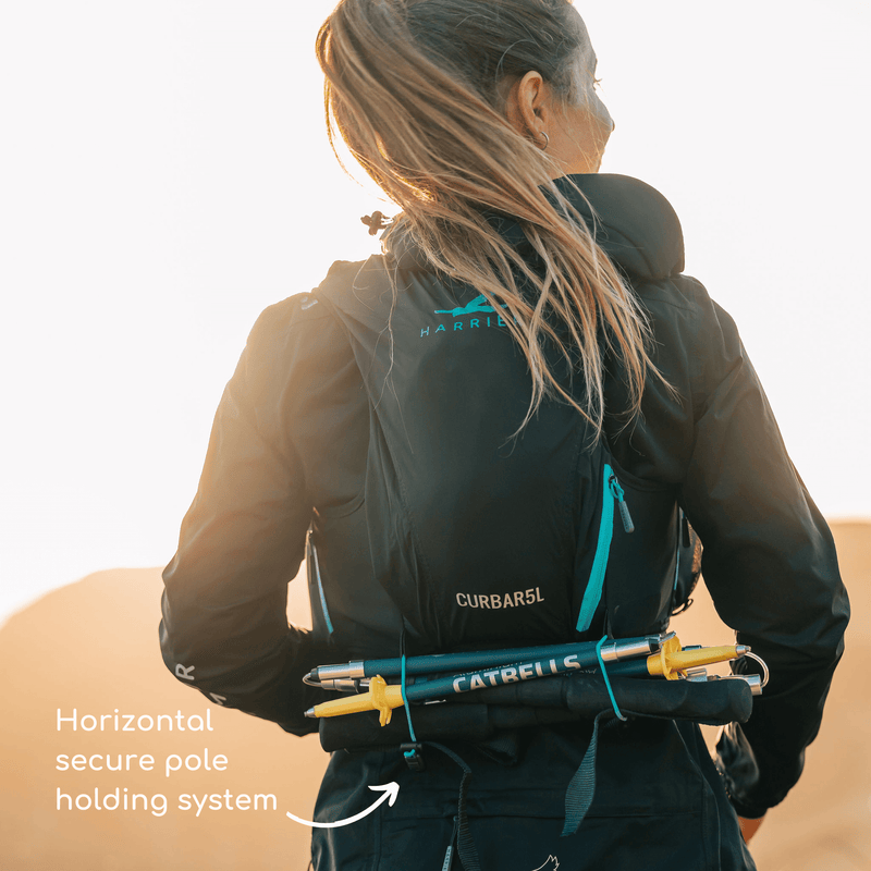 A woman demonstrating how running poles can be attached to the Curbar 5L running hydration vest.