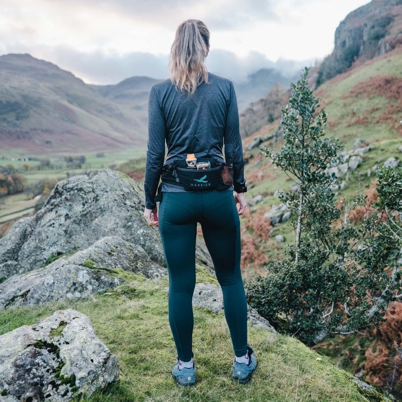 A woman in the countryside wearing a waist bag. 