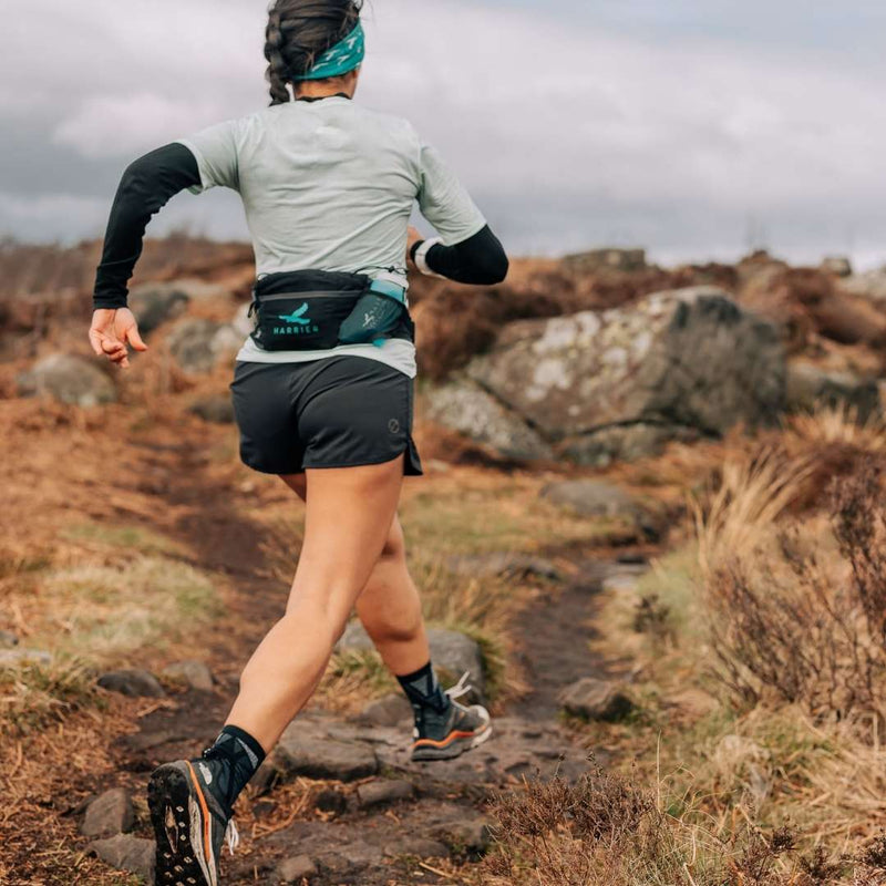 A woman wearing a waist bag running in the countryside. 